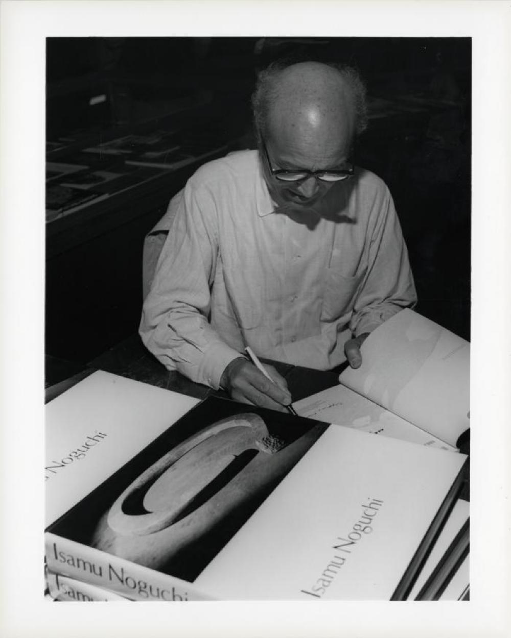 Noguchi signing catalogues at opening reception for "Noguchi's Imaginary Landscapes," Detroit Institute of Fine Arts, April 10 – June 10 1979 (travel from Walker Art Center).